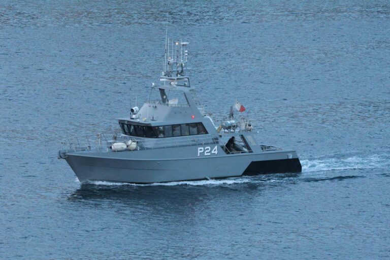 Military patrol boat cruising through ocean waters.